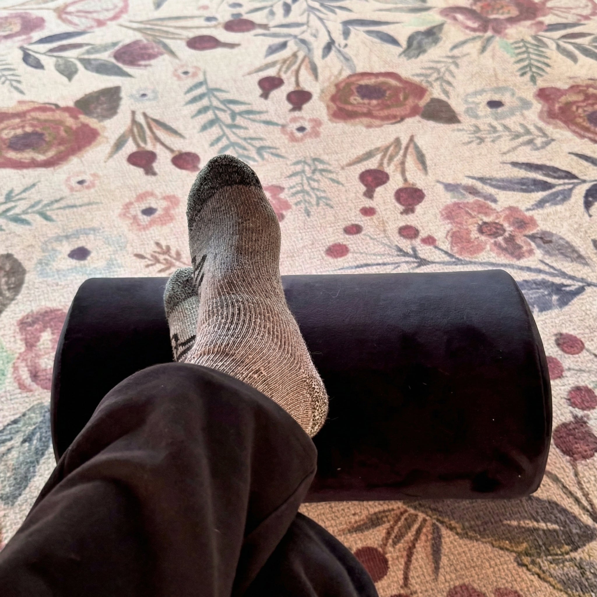 Person using a footrest on a floral-patterned floor