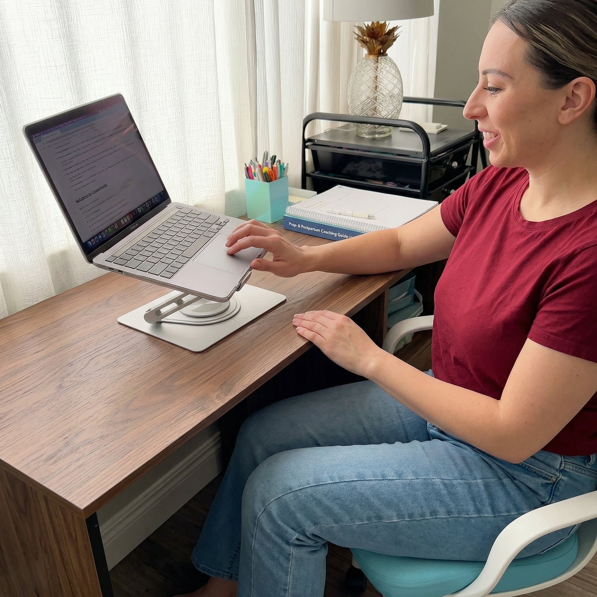 Woman using a laptop placed on Serenform Elevate Laptop Stand at a desk in a home office setting