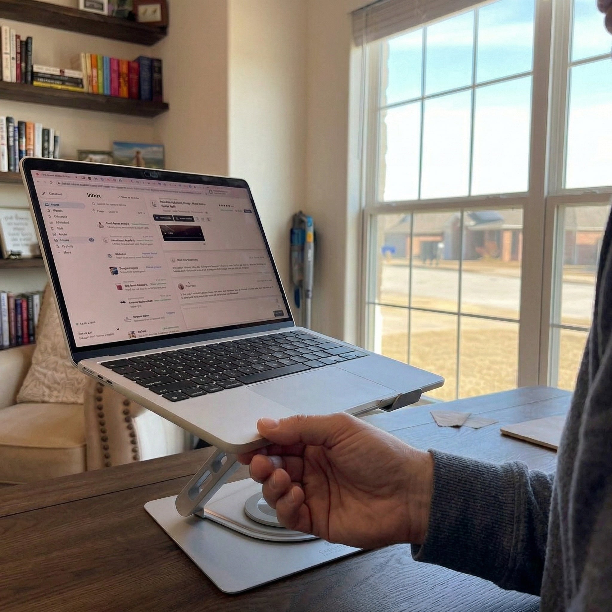 Person rotating laptop on the Serenform Elevate Laptop Stand with one hand in home office